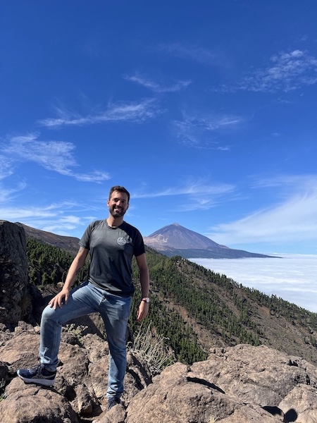 About me Kilian Jiménez sonriendo a la cámara de forma casual en la montaña